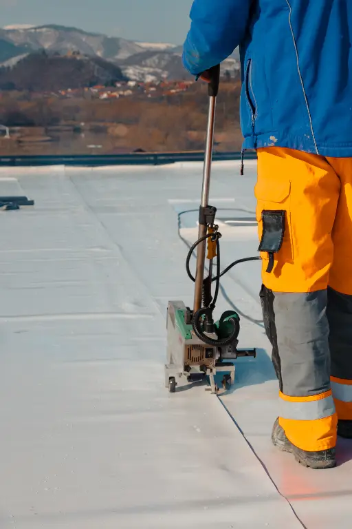etancheite toiture metallique Travailleur entretien toit plat avec machine d'étanchéité.